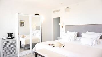A hotel room with a large bed, bedside tables, a wardrobe, and a mirror.