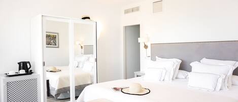 A hotel room with a large bed, bedside tables, a wardrobe, and a mirror.