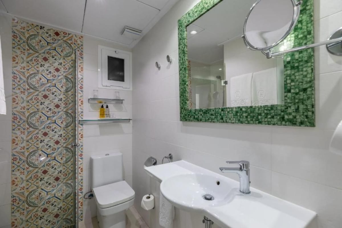 A bathroom with a toilet, sink, and mirror.