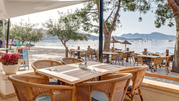 An outdoor dining area with wicker furniture and a view of the sea. - Hoposa Bahía (Pollenca)