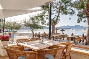 An outdoor dining area with wicker furniture and a view of the sea. - Hoposa Bahía (Pollenca)
