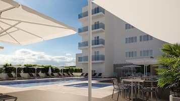 Zona de piscina moderna al aire libre con sillones de relax, sombrillas y mobiliario para comer.