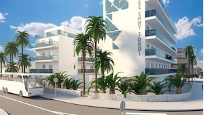 Un hotel moderno con una fachada geométrica destacada, múltiples balcones y palmeras.