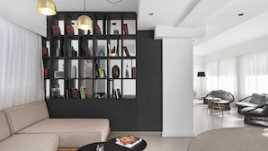 Una sala de estar moderna con un sofá color beige, una mesa de centro negra, un tapete redondo y una estantería negra con objetos decorativos.