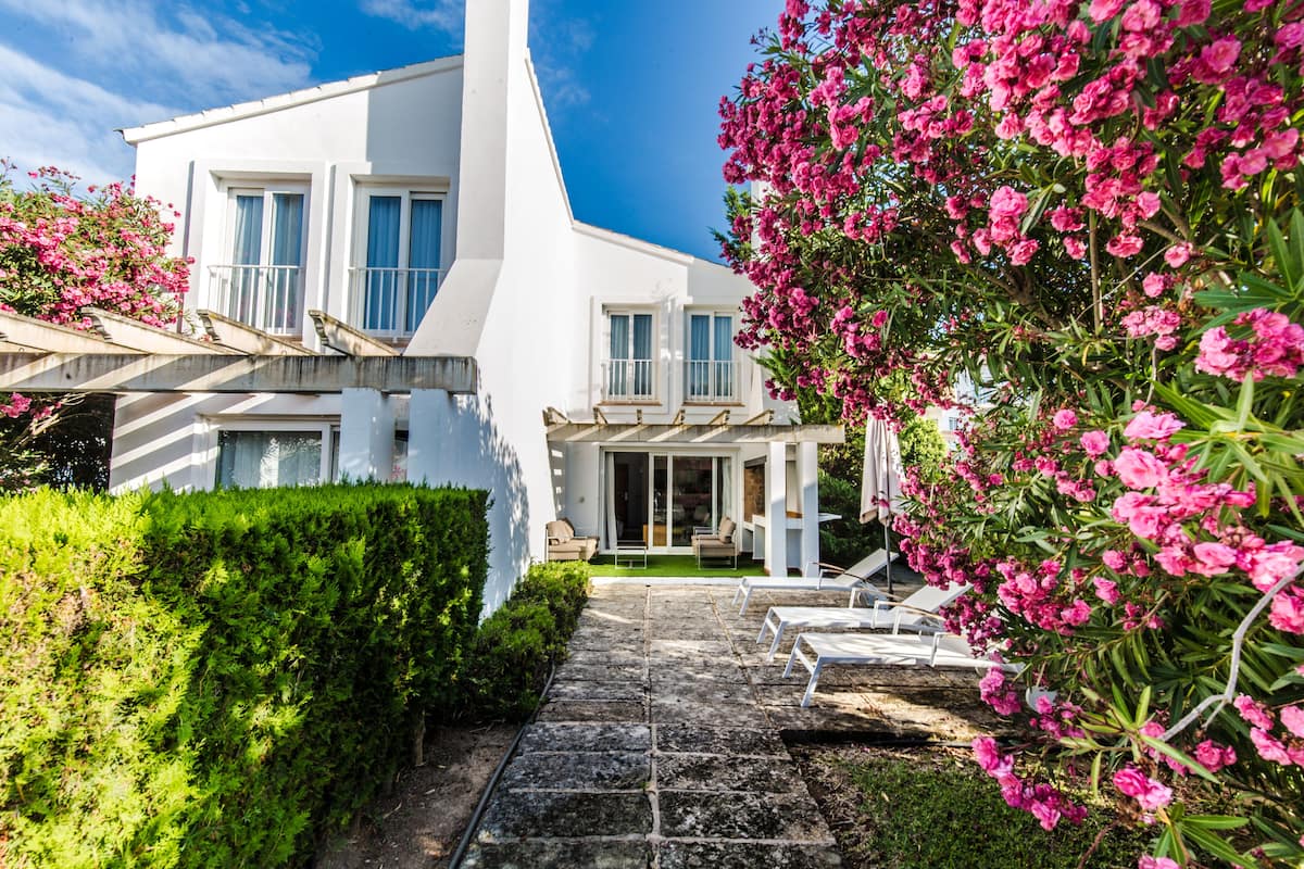 Una casa moderna blanca con un camino de piedra que lleva a un porche cubierto.