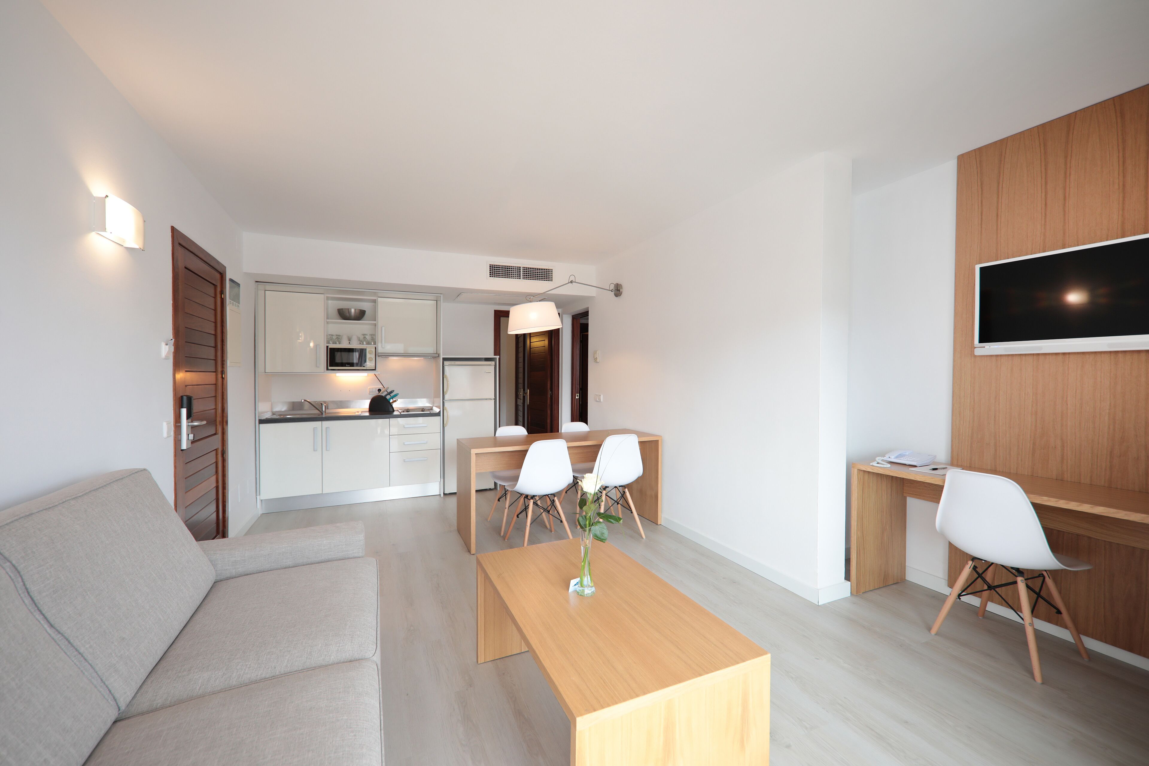 Un salon moderne avec un canapé, une table basse en bois et un coin repas comprenant des chaises et une table.
