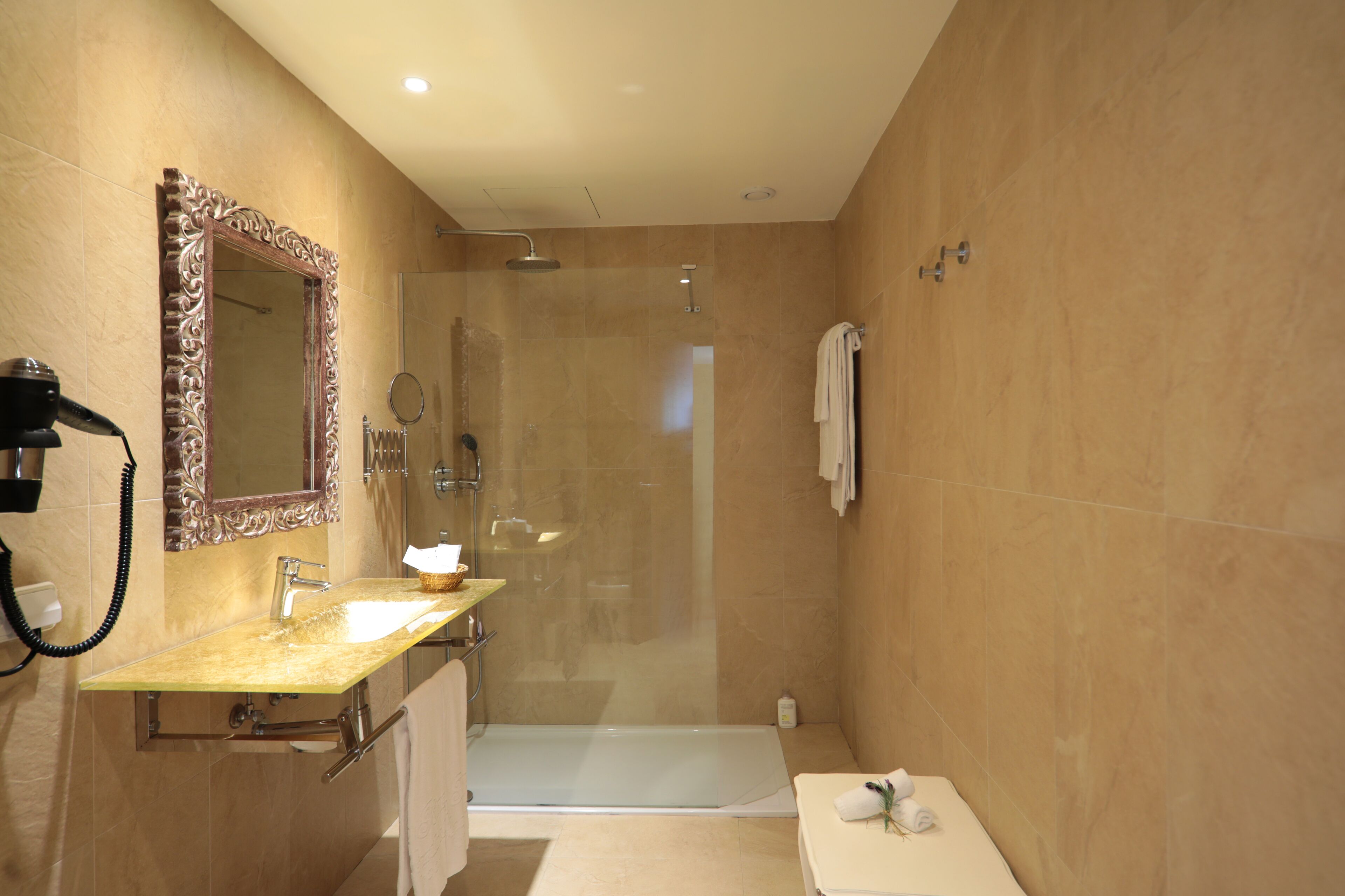 A modern bathroom with a vanity, a large mirror, a shower, and a towel rack.
