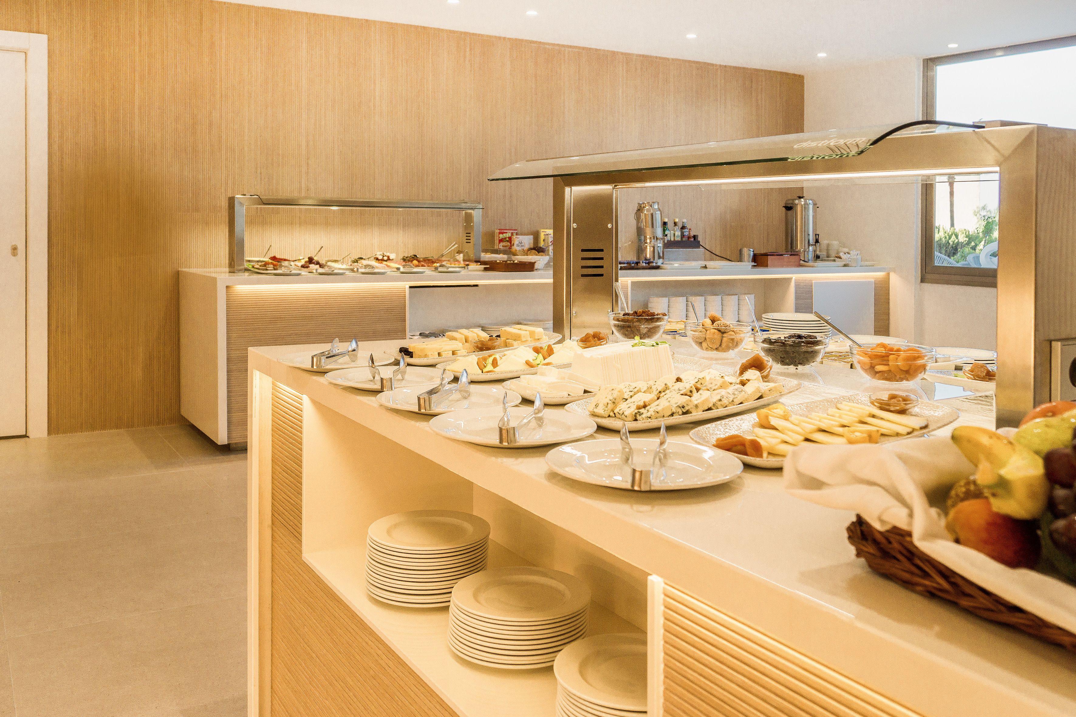 A buffet setup with multiple serving stations, including plates, bowls, and a fruit basket.