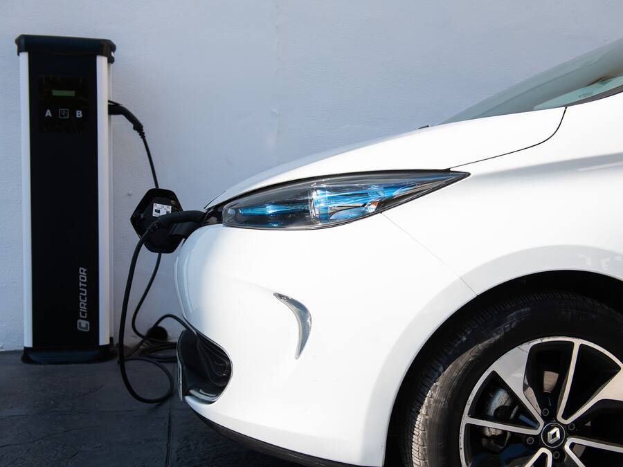 A white car parked next to a charging station.