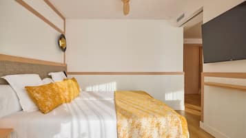 Una habitación de hotel moderna con cama, mesita de noche, televisión y un diseño de techo de madera.