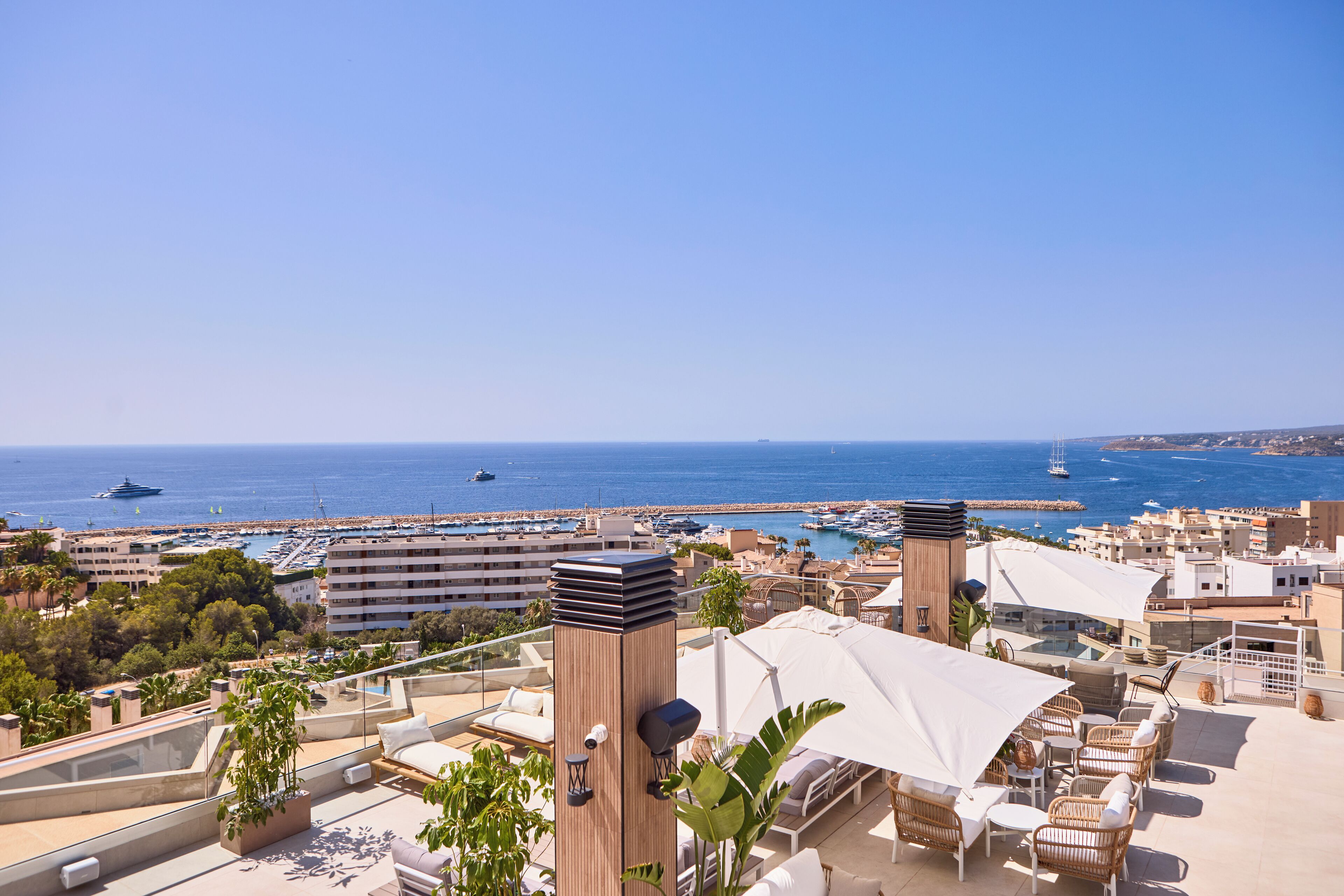 Terraza en la azotea con mobiliario exterior, vista al mar y un puerto deportivo al fondo.