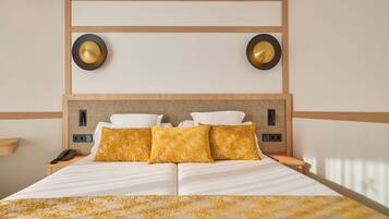 A hotel room with a large bed, two bedside tables, a wall-mounted phone, and two wall sconces.