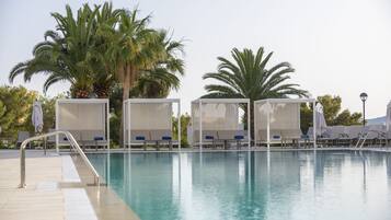 Un área de piscina con sillas de descanso y palmeras.