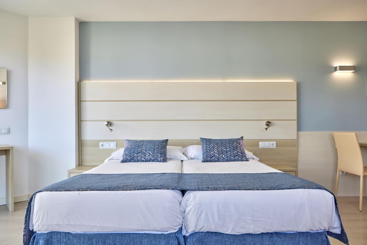 A double bed with a wooden headboard, two pillows, and a bedside table.