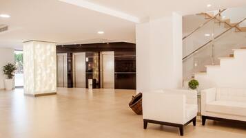 A spacious lobby with a modern staircase, a white sofa, and a large pillar.