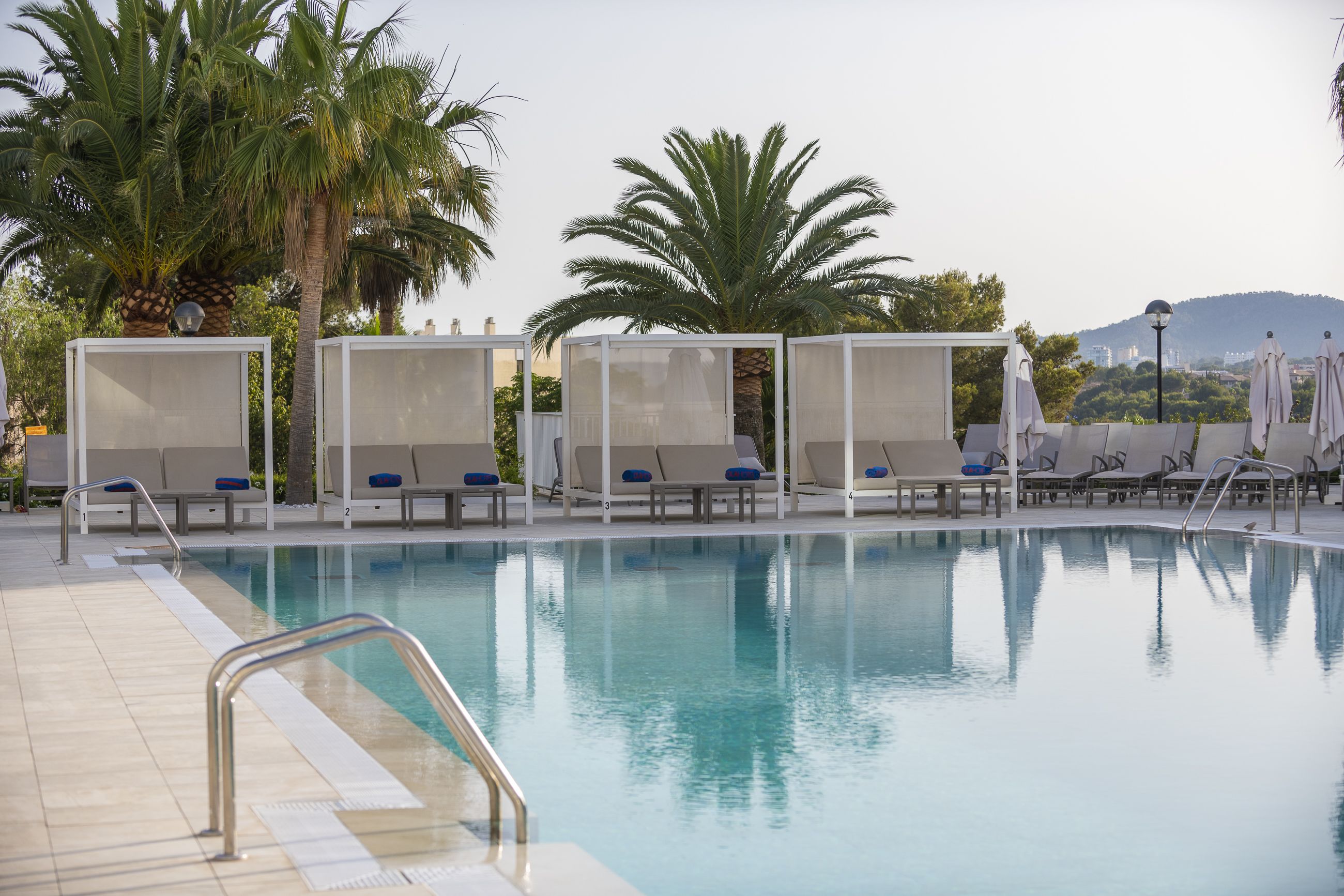 A pool area with lounge chairs and palm trees.