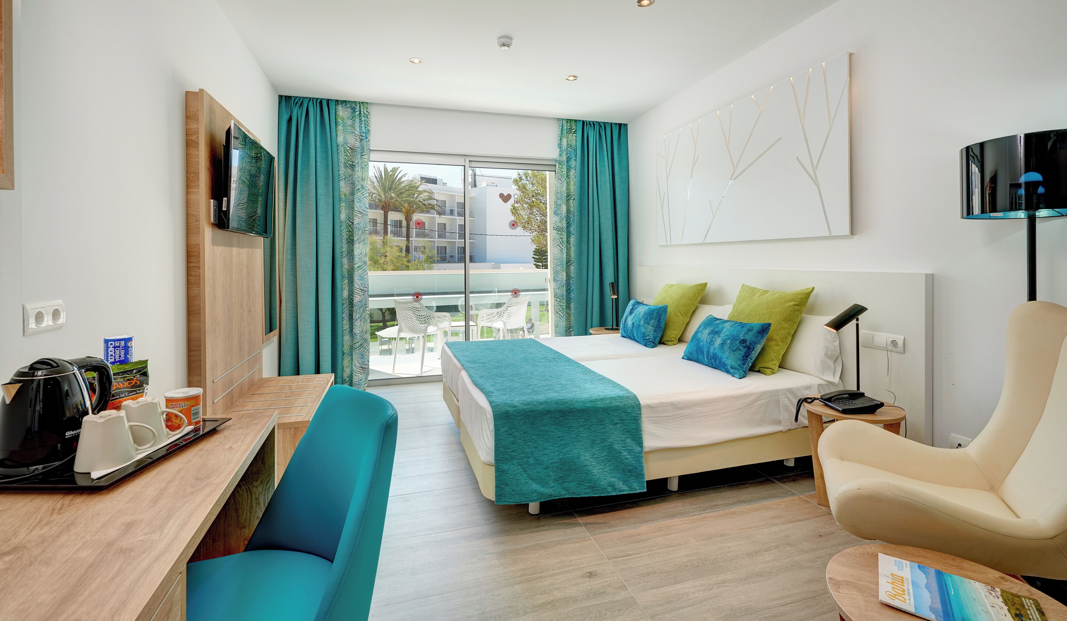 A hotel room with a bed, a desk, a chair, a TV, and a balcony with a view.