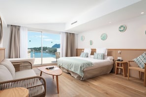 Ein Hotelzimmer mit einem großen Bett, einer Couch, einem kleinen Tisch und Meerblick.