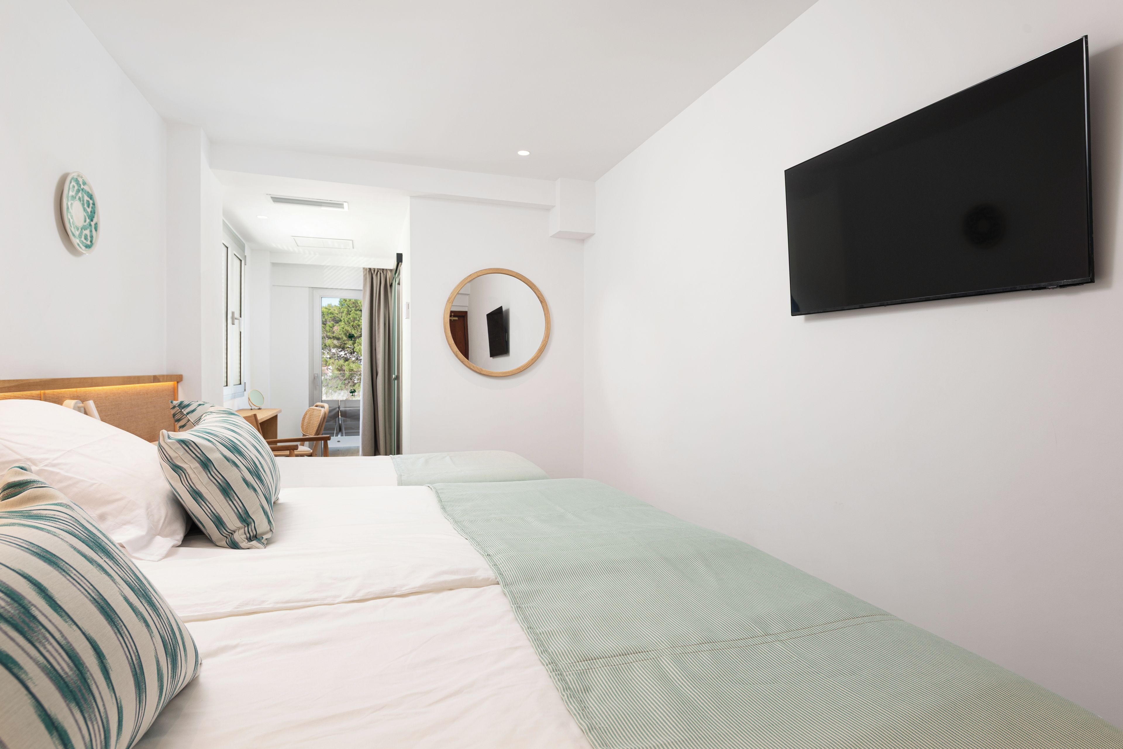 Habitación de hotel con cama, escritorio, silla, televisor y ventana.