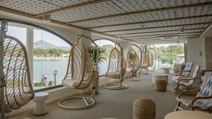 Una habitación con ventanas amplias, sillas de mimbre y vistas a un lago.