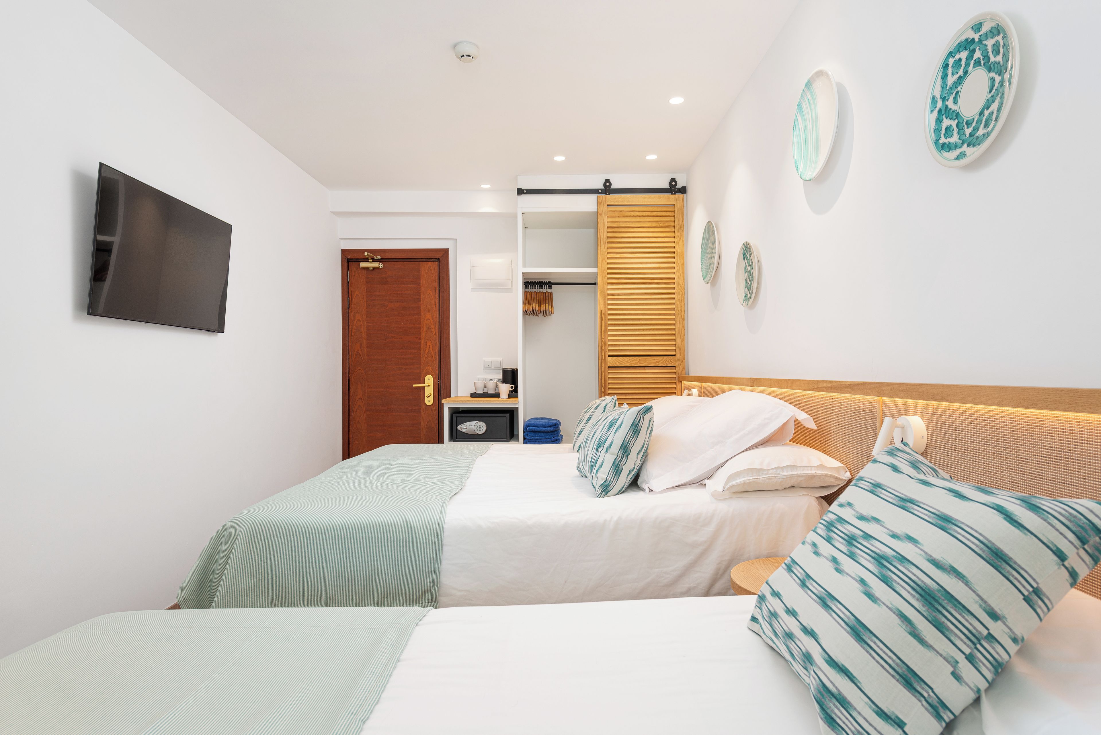 Una habitació d'hotel amb un llit, una televisió, un armari i una taula de nit.