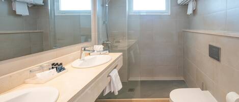 A modern bathroom with two sinks, a toilet, and a glass-enclosed shower.