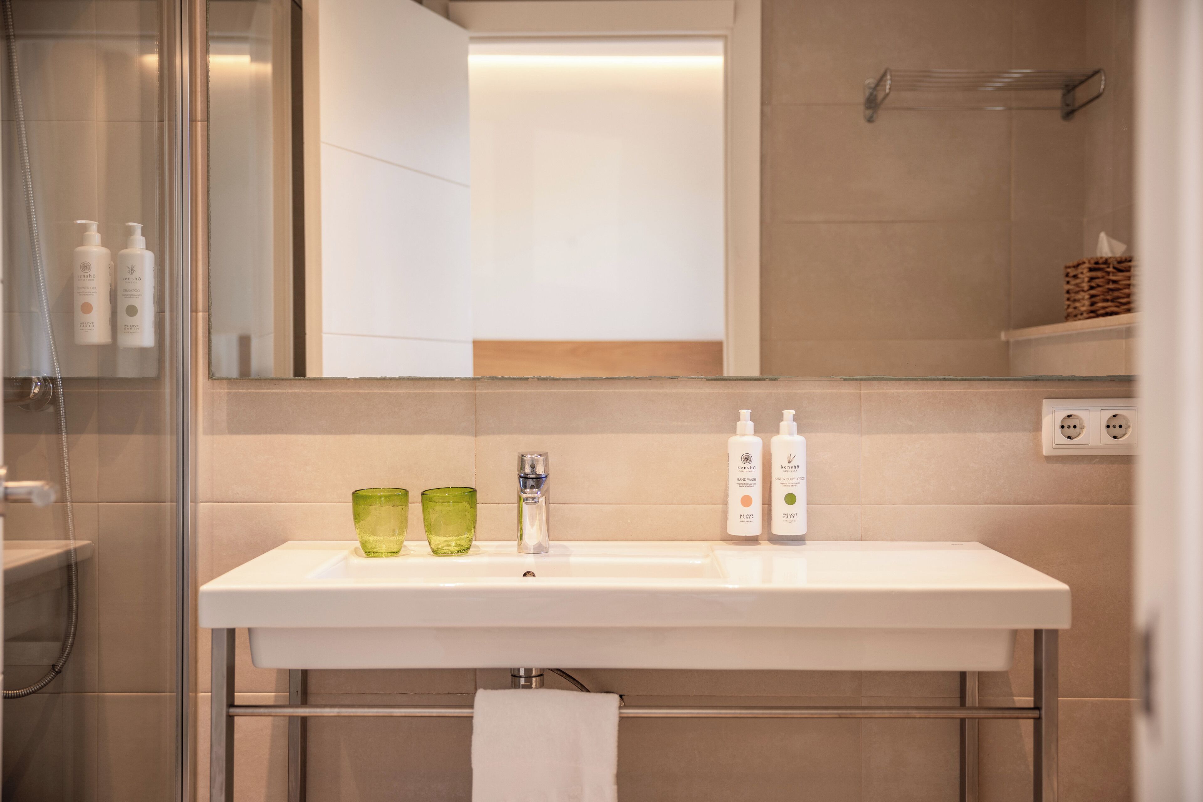 A bathroom with a white sink, green glasses, and two bottles of lotion.