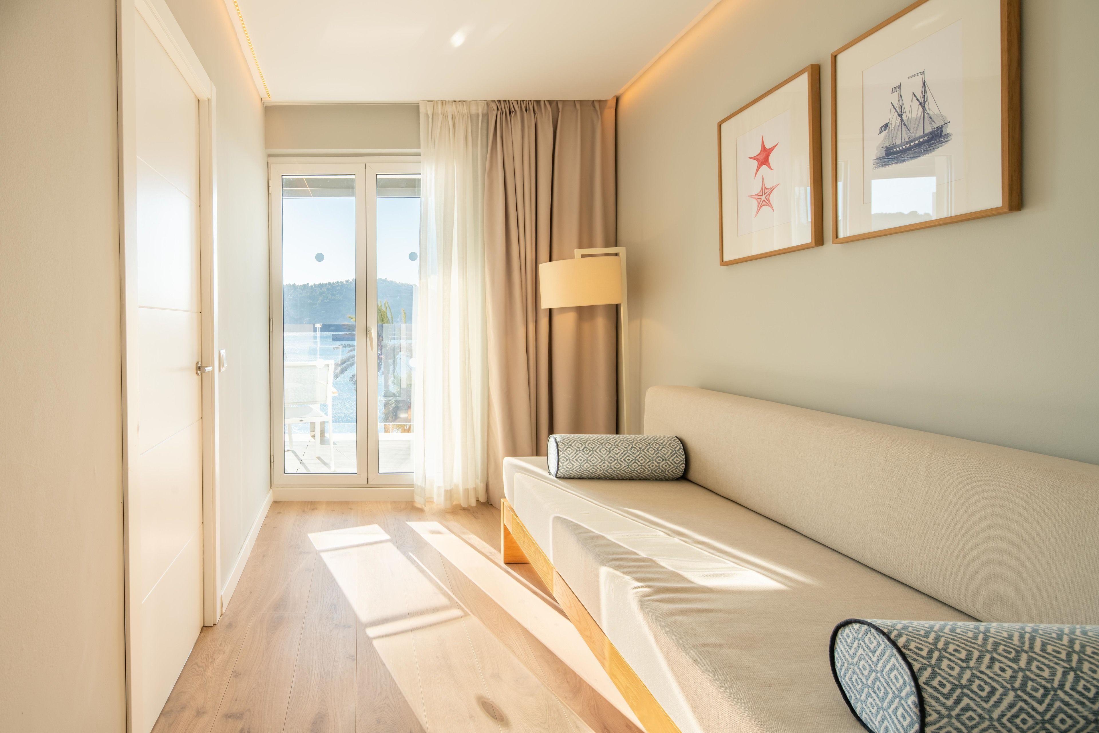 Ein modernes Hotelzimmer mit einer Couch, einer Lampe und Blick ins Freie.