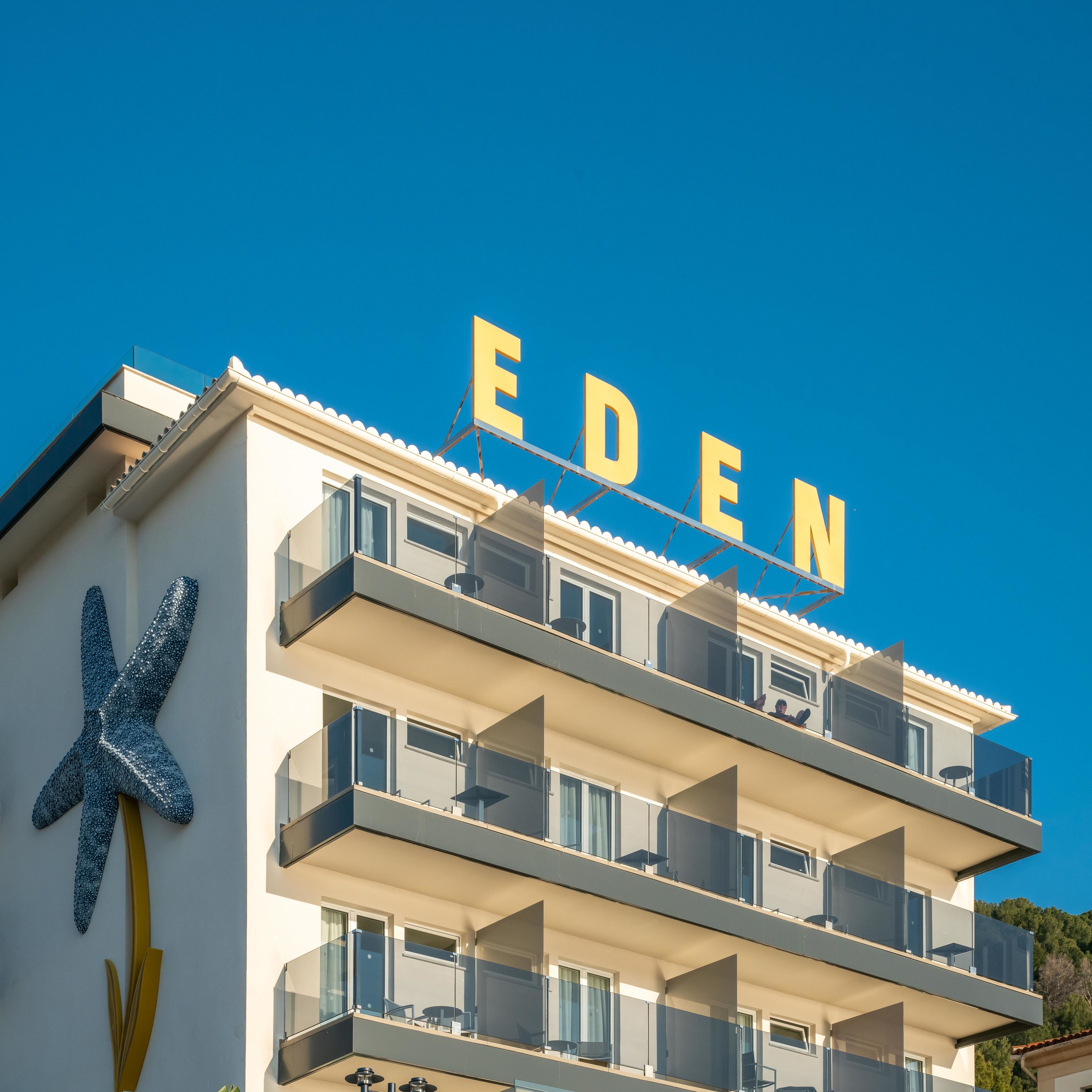 Un hôtel à plusieurs étages, doté de balcons et d’une grande enseigne portant le nom « EDEN ».