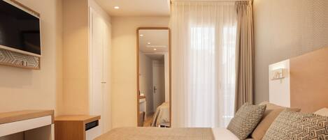 A hotel room with a bed, a TV, a desk, and a mirror.