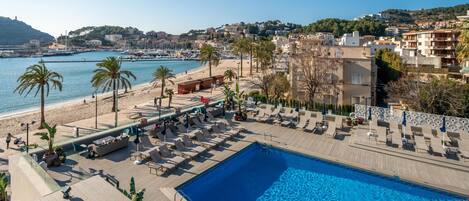 Un espace piscine avec des chaises longues et une vue sur la plage et la ville.