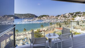 A balcony with a view of a marina, beach, and hillside buildings.