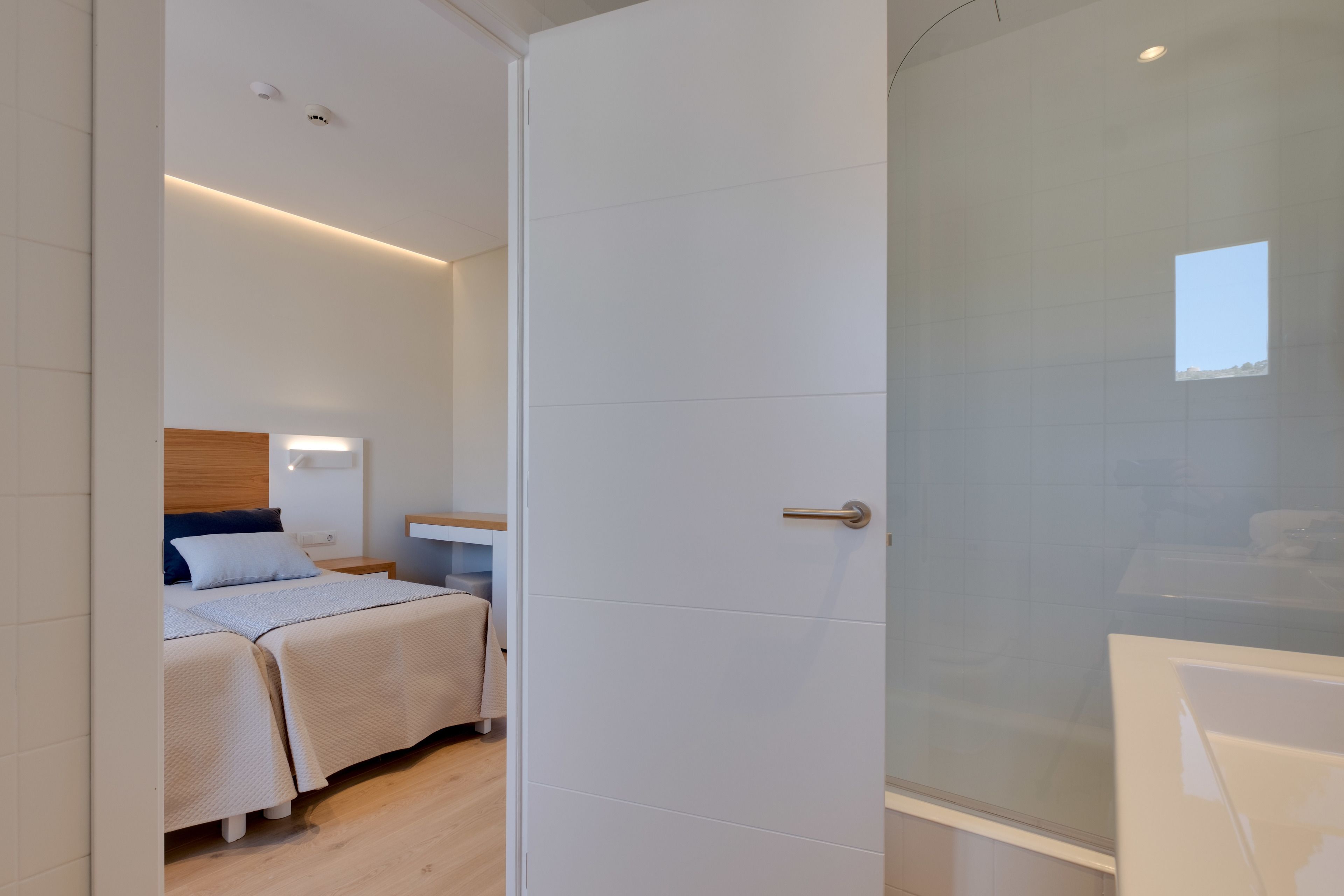Een moderne hotelkamer met een groot bed, nachtkastjes en een douchehoek.