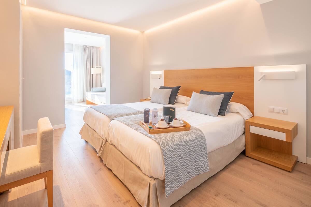 A modern hotel room with a large bed, bedside tables, a desk, and a chair.