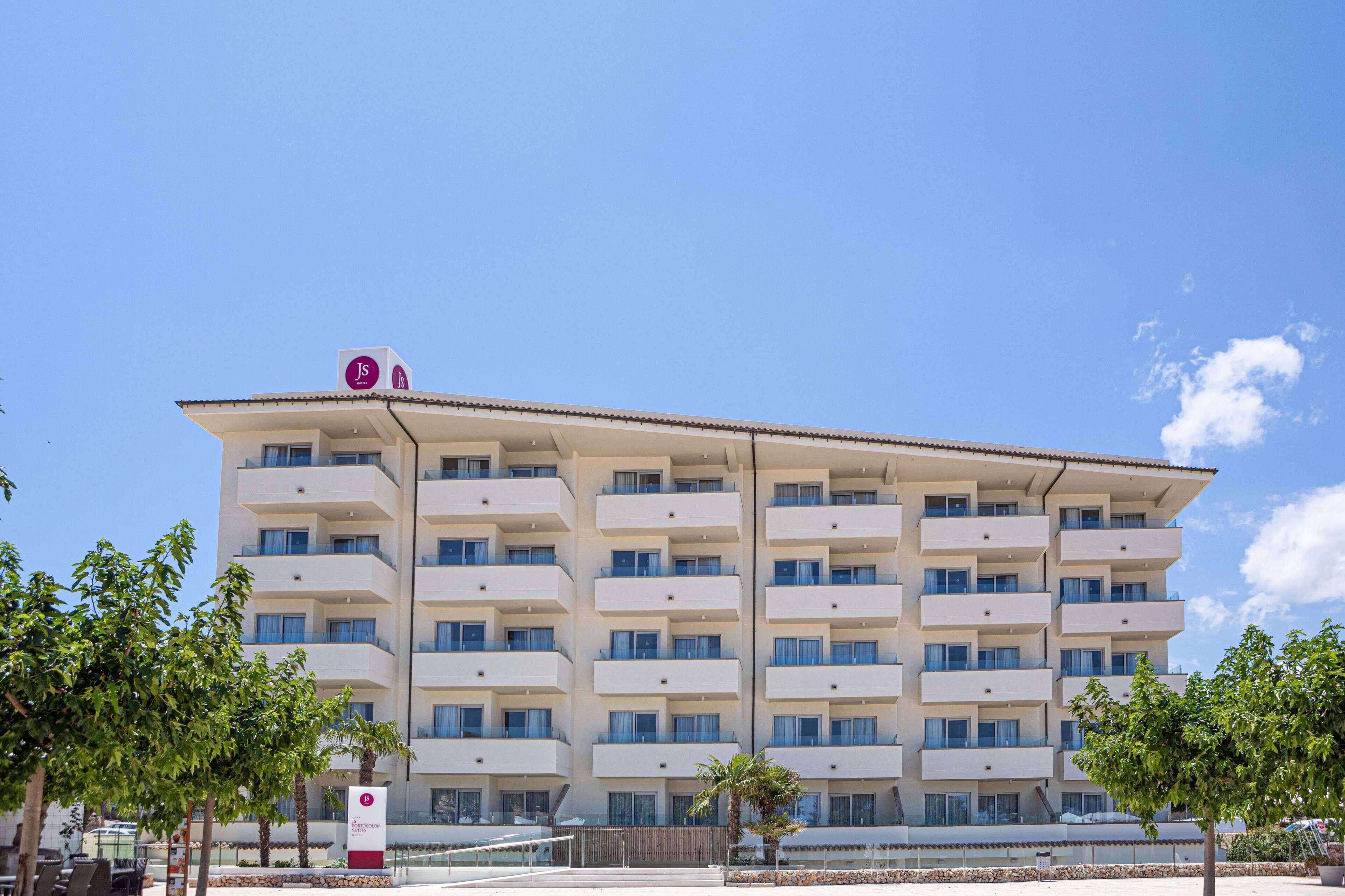 A multi-story hotel with a flat roof, balconies on each floor, and a clear sky.