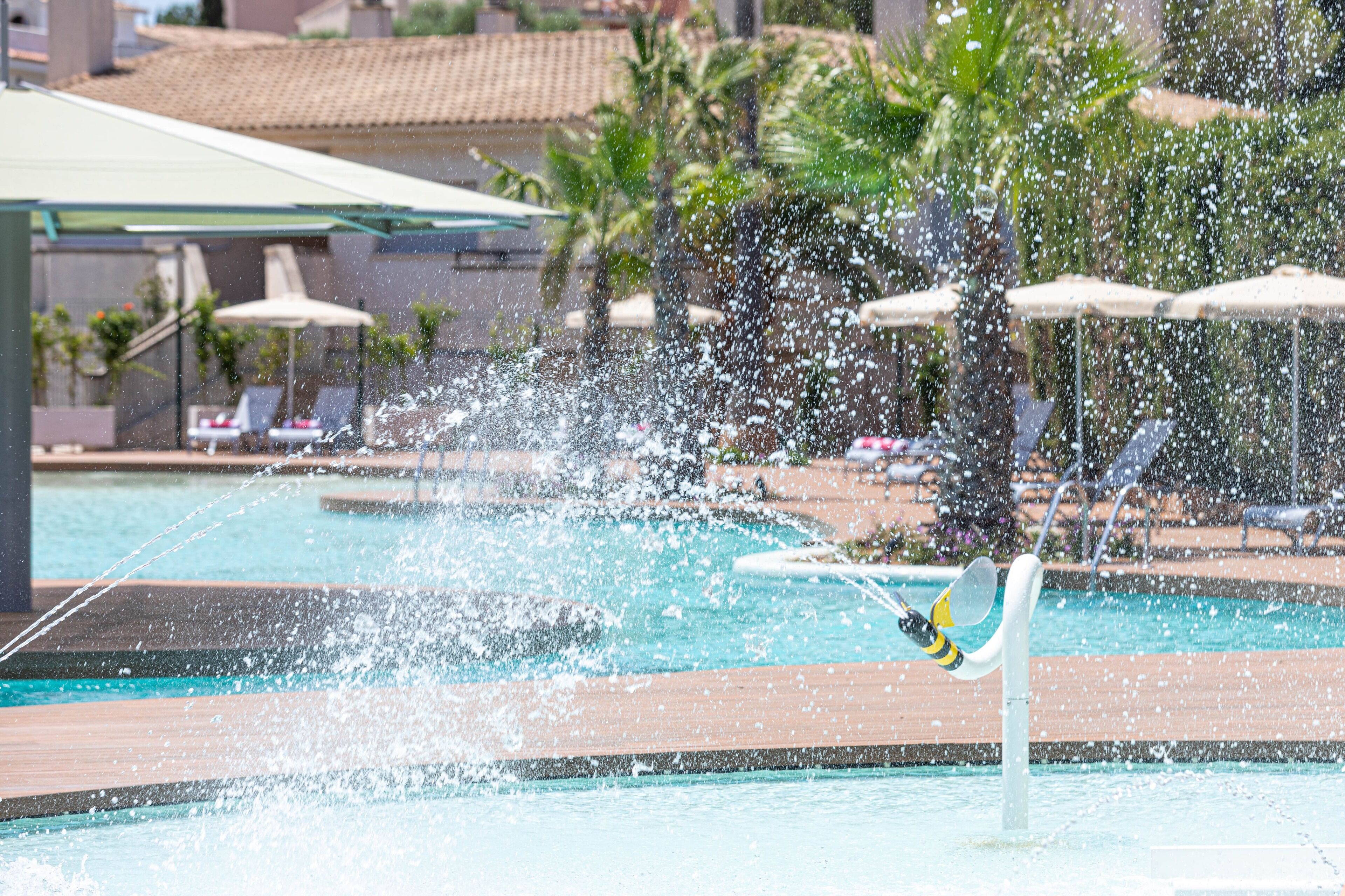 A pool area with a water feature and lounge chairs.