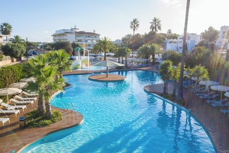 Una piscina al aire libre, sombrillas, sillones reclinables de piscina. Hotel JS PortoColom Suites