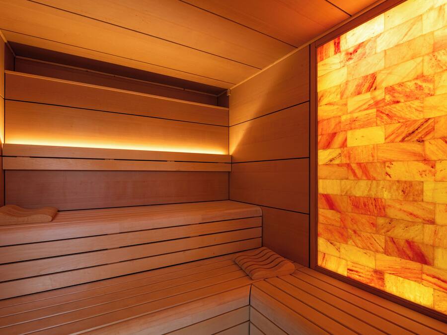 Una sauna con bancos de madera y una pared de azulejos.
