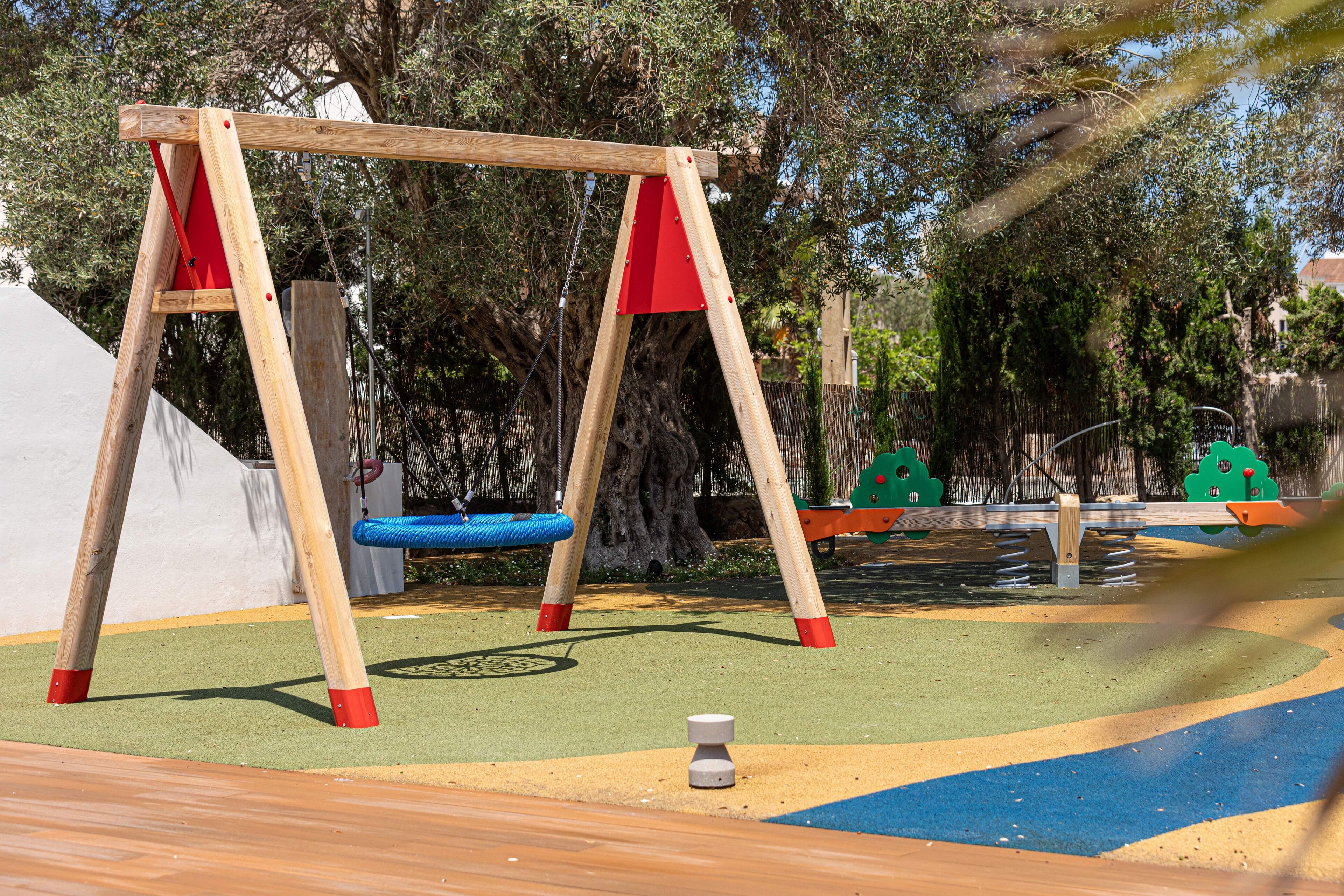 A playground with a wooden swing set and a blue swing.