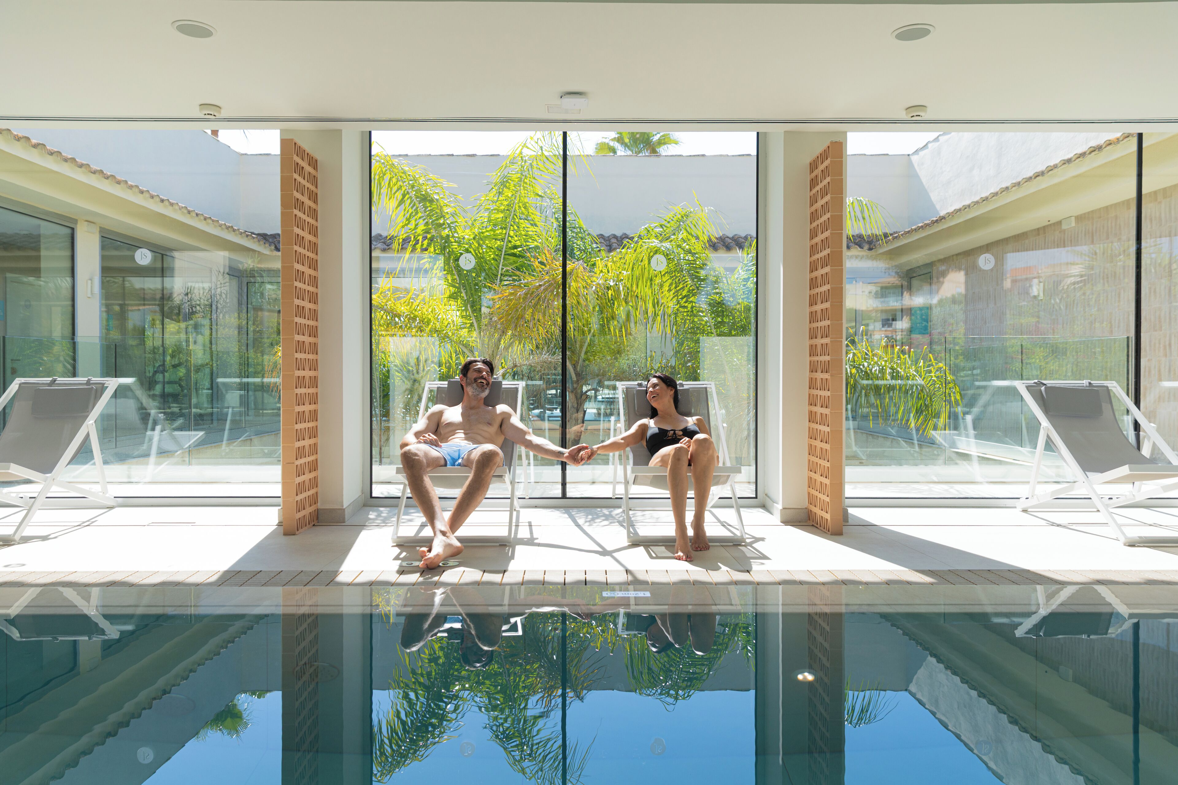 A modern indoor pool area with glass walls and a clear view of the outdoors.