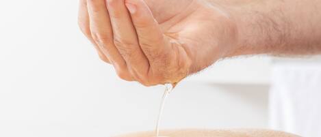 A hand pouring a liquid onto a surface.