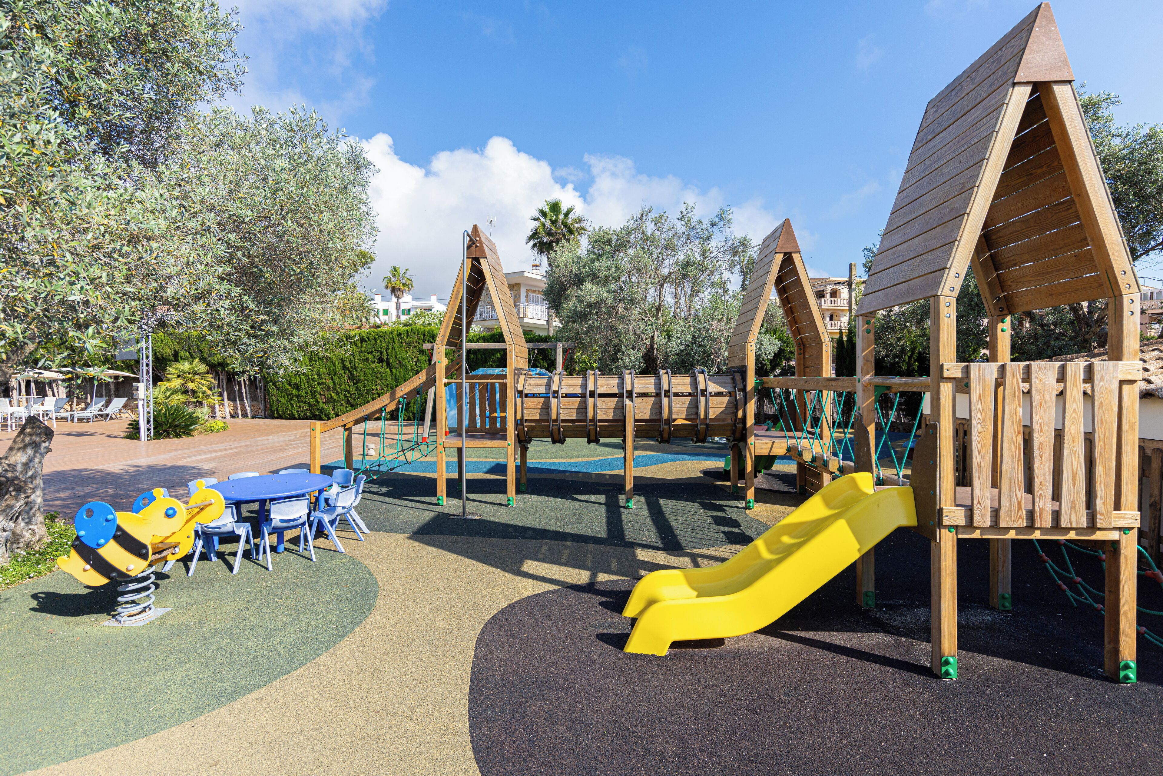 A playground with a slide, swings, and a table with chairs.