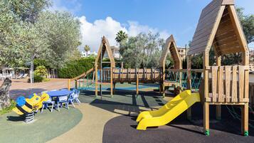 A playground with a slide, swings, and a table with chairs.