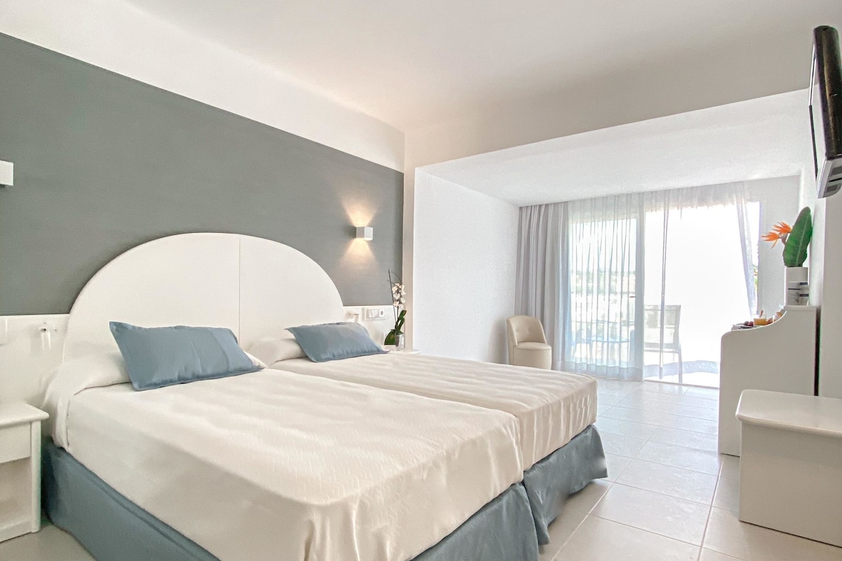 Une chambre d’hôtel moderne, dotée d’un grand lit, d’un bureau et offrant une vue sur l’extérieur.