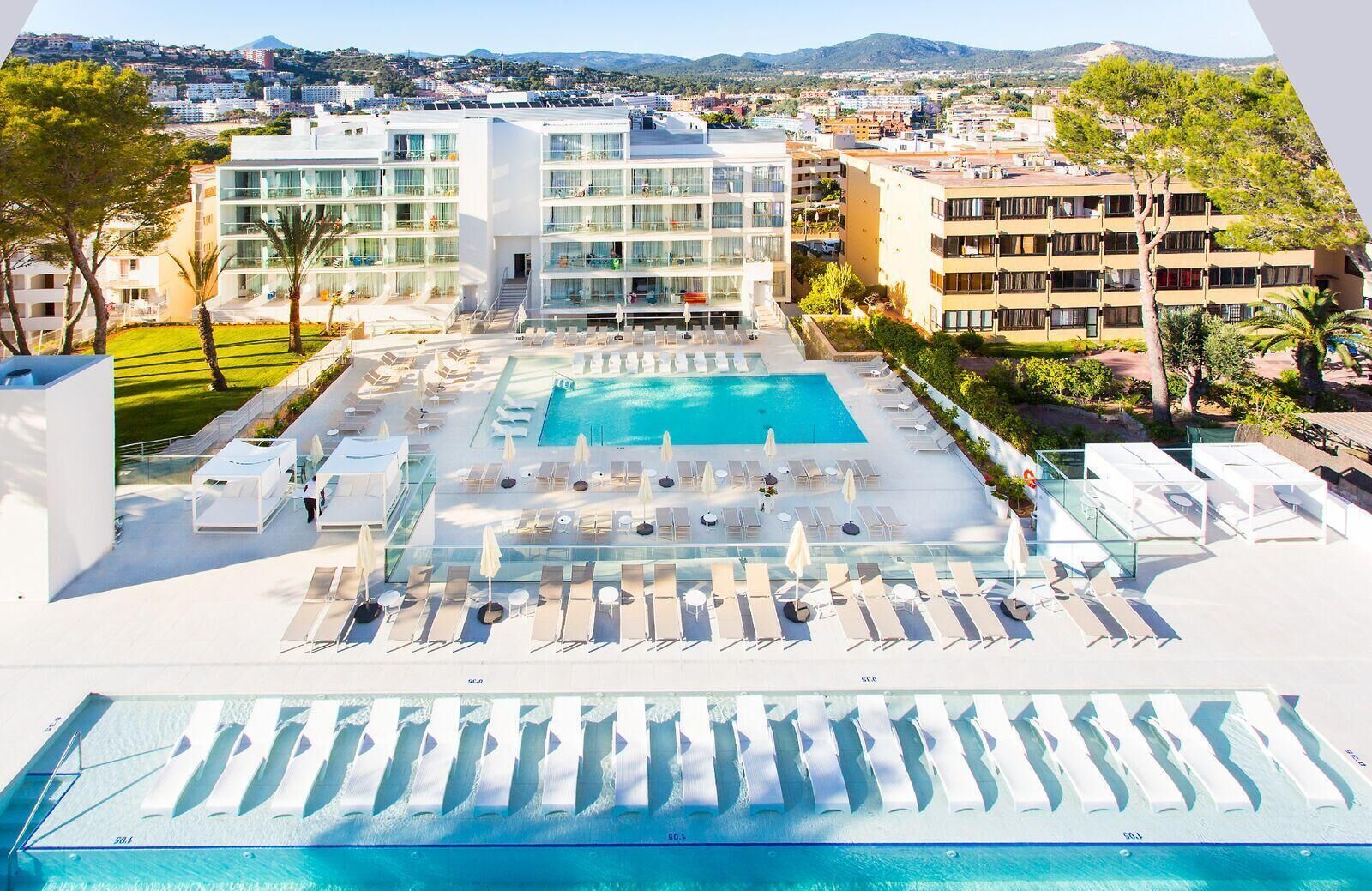 Un hotel con piscina, tumbonas y vistas de la ciudad.