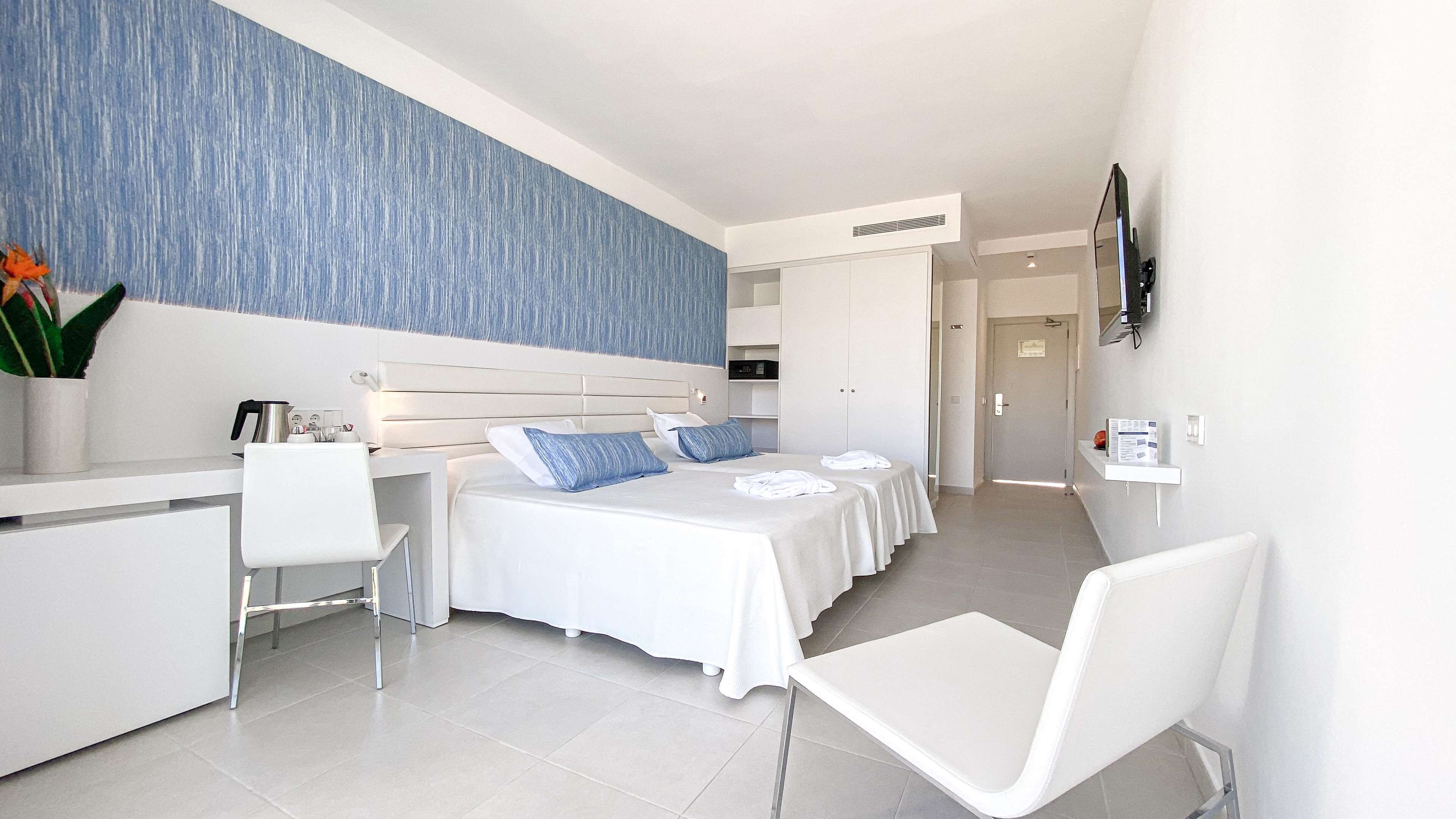 A modern hotel room with a large bed, a desk, and a chair.