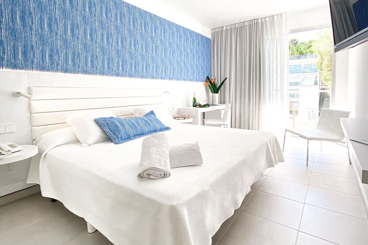 Une chambre d’hôtel équipée d’un lit, d’un bureau, d’une chaise, d’une télévision et d’une fenêtre avec des rideaux.