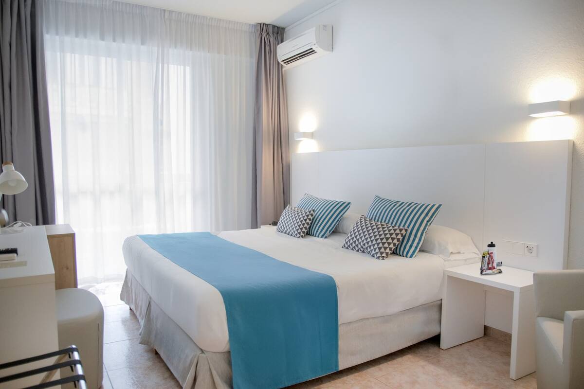 A hotel room with a large bed, bedside tables, a desk, and a chair.