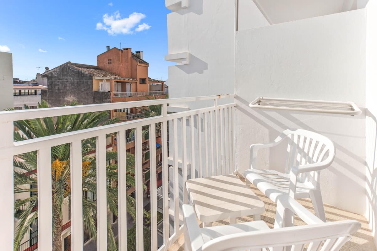 A balcony with white railings, a white chair, and a small table.