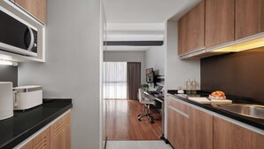 Une cuisine moderne avec des meubles en bois, un four à micro-ondes encastré et un évier en acier inoxydable.